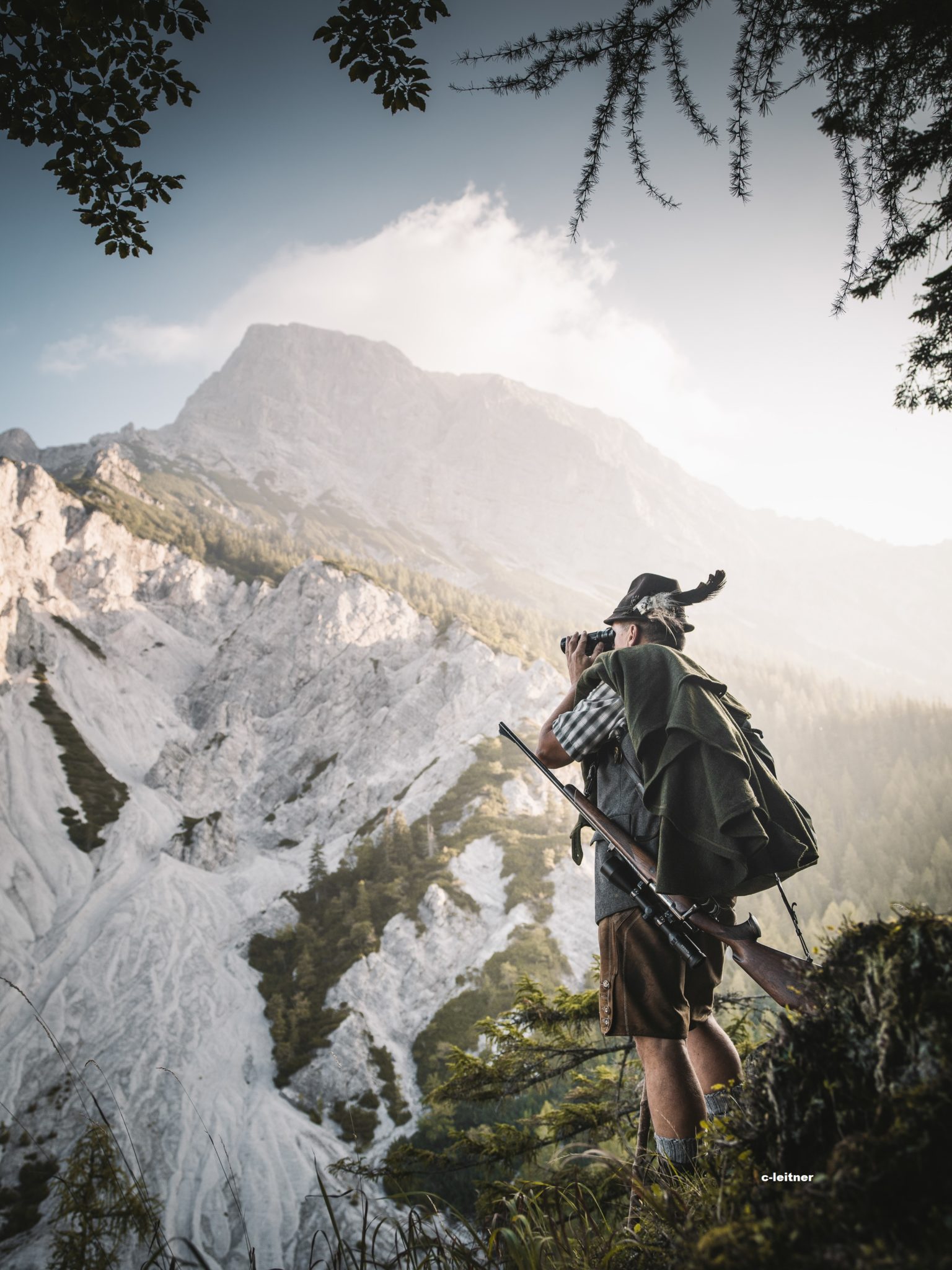 Ein Jäger im Gesaeuse beobachtet Gämsen mit dem Fernglas
